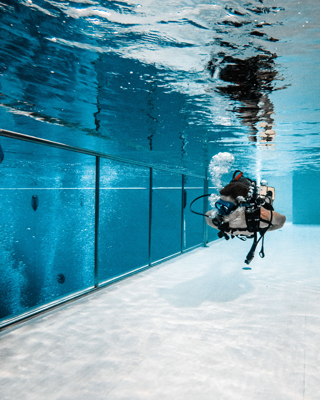 Dive while breathing underwater. Once you have become familiar with the scuba equipment in shallow water, you begin a gradual and slow descent to depth.